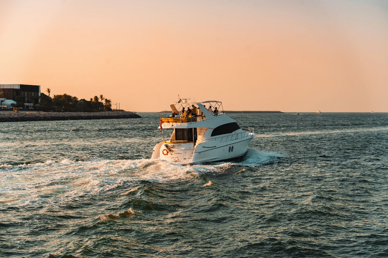 A private motor yacht cruising in Dubai at sunset, with the entire boat in view