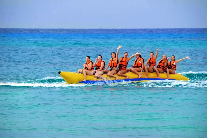 A group wearing life jackets enjoying a yellow banana boat ride on clear water