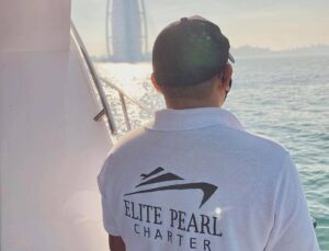 elite pearl charter - a man staring at the horizon with the view of burj al arab from a yacht boat